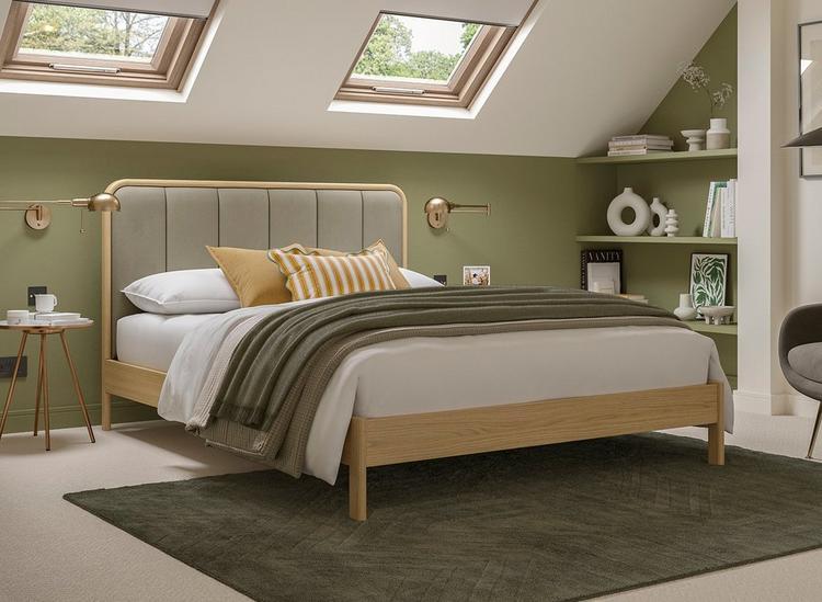 Wooden bed frame with panelled velvet headboard, styled in a green and white bedroom.
