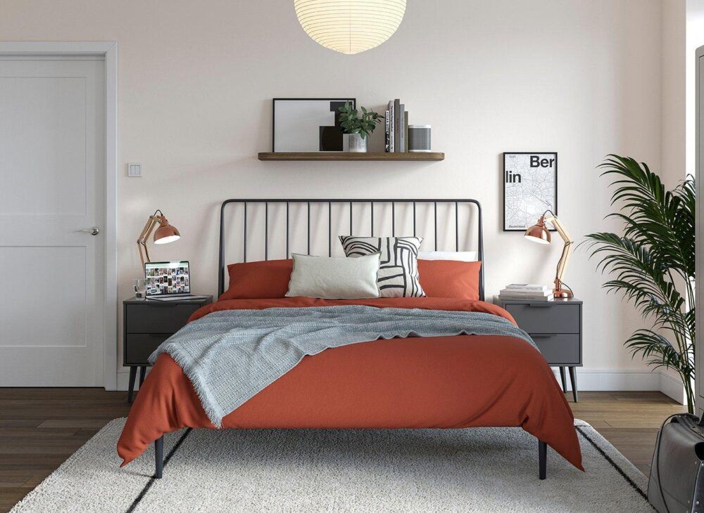 Renter-friendly bedroom ideas - Black metal bed frame with deep rust red bed sheets in a white room