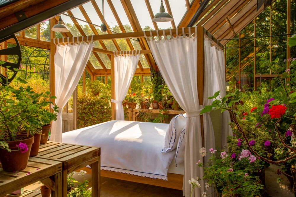 Designing an English country bedroom with Sophie Conran - Arbor four poster bed with wood and linen drapes pictured in a spectacular greenhouse