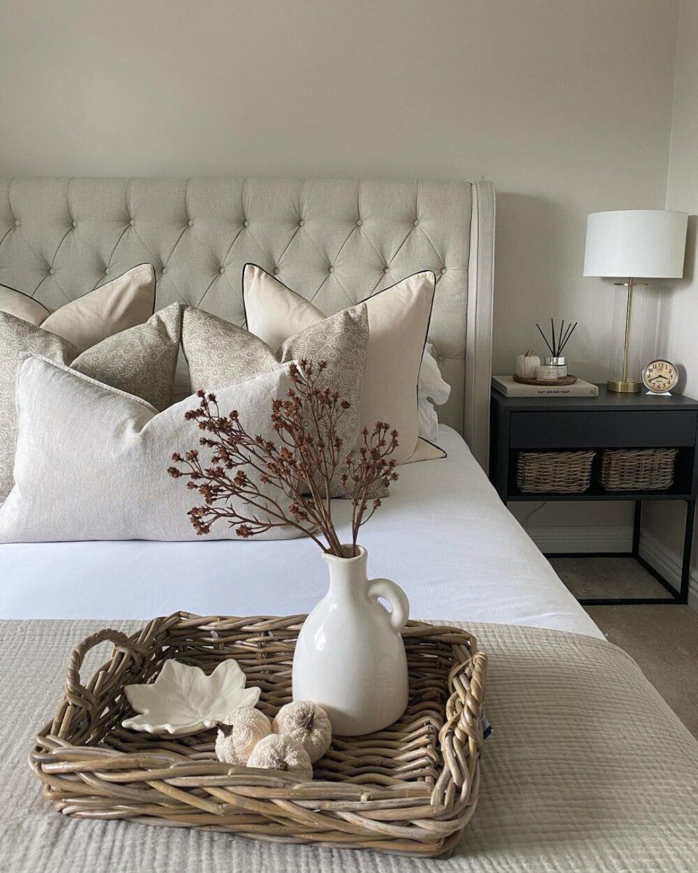 Hygge bedroom idea s- Beige buttoned bed frame, styled with flowers and woven accents.