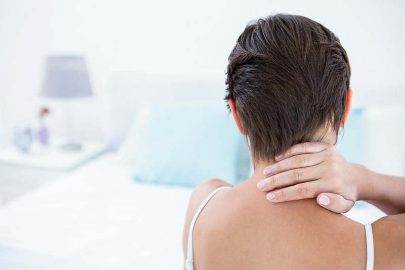 woman holding the back of her neck in pain