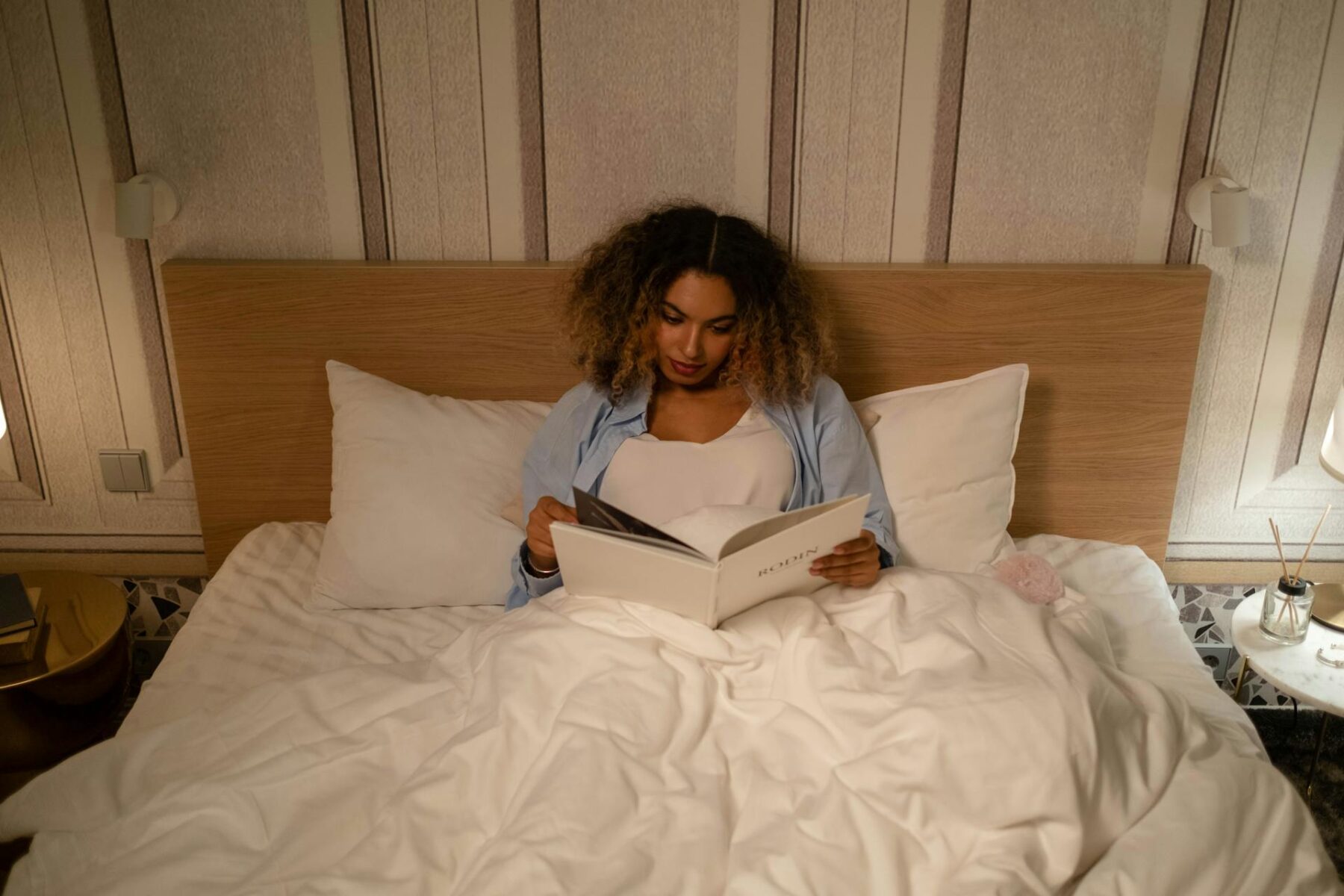 Woman enjoys a peaceful evening reading in bed, capturing a moment of leisure and relaxation.